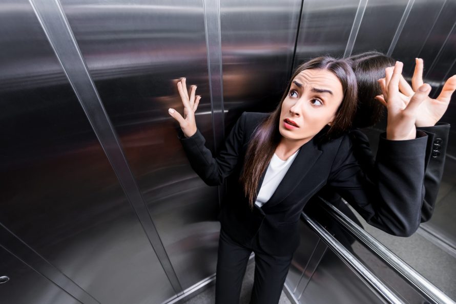 young scared businesswoman suffering from claustrophobia in elevator